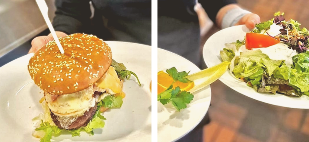 Ein Kellner serviert einen Hamburger und einen Salat.